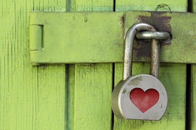 Ett hänglås med ett rött hjärta hänger på en grön dörr